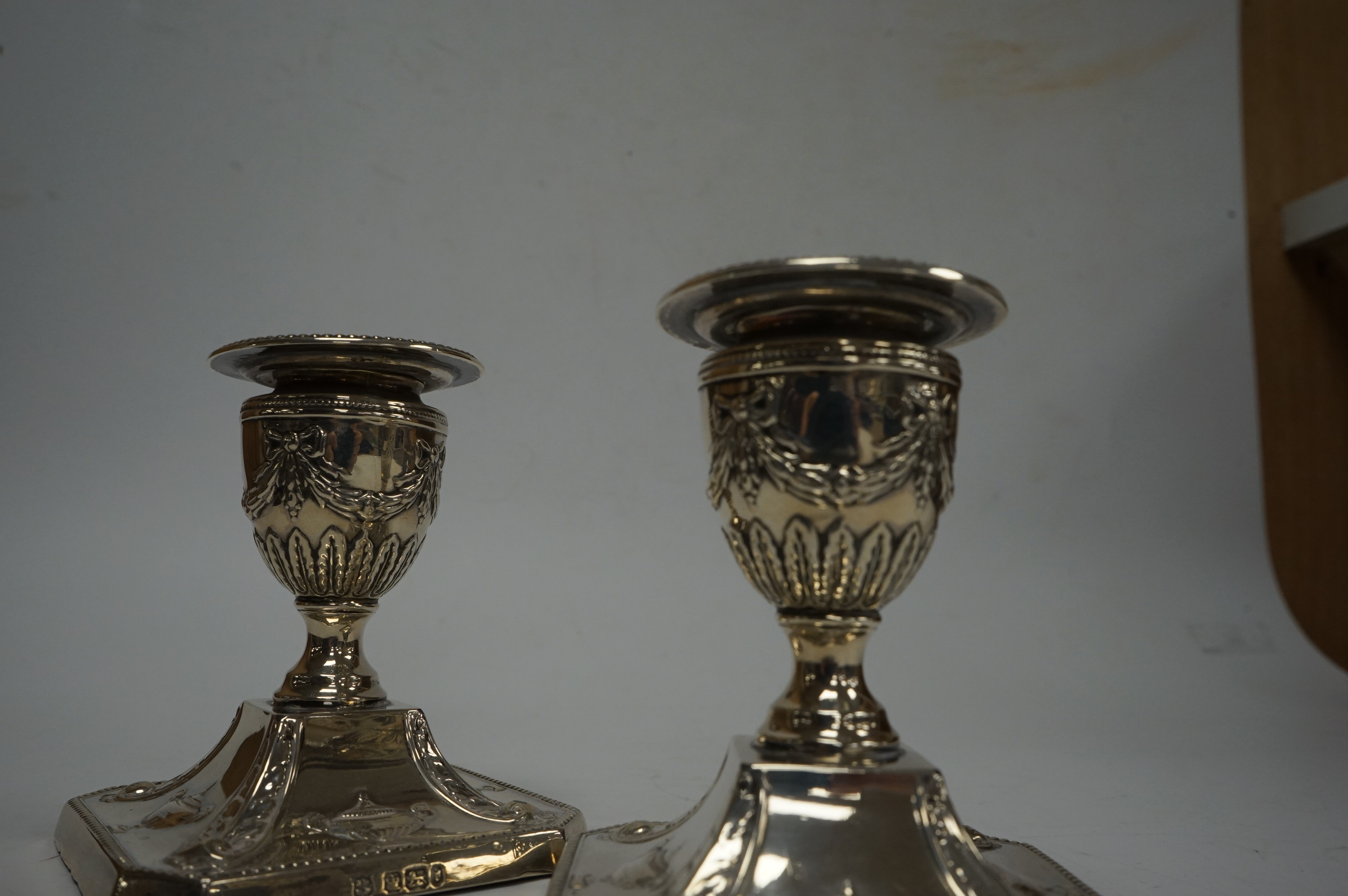 A pair of Edwardian silver mounted dwarf candlesticks, with swag and ribbon decoration, by James Deakin & Sons, Sheffield, 1901, height 92mm, weighted. Condition - poor to fair